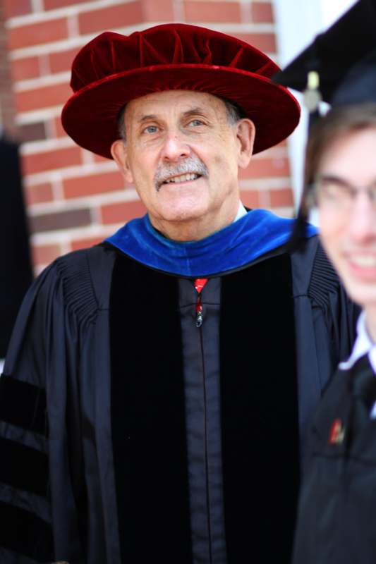 a man wearing a black robe and a red hat