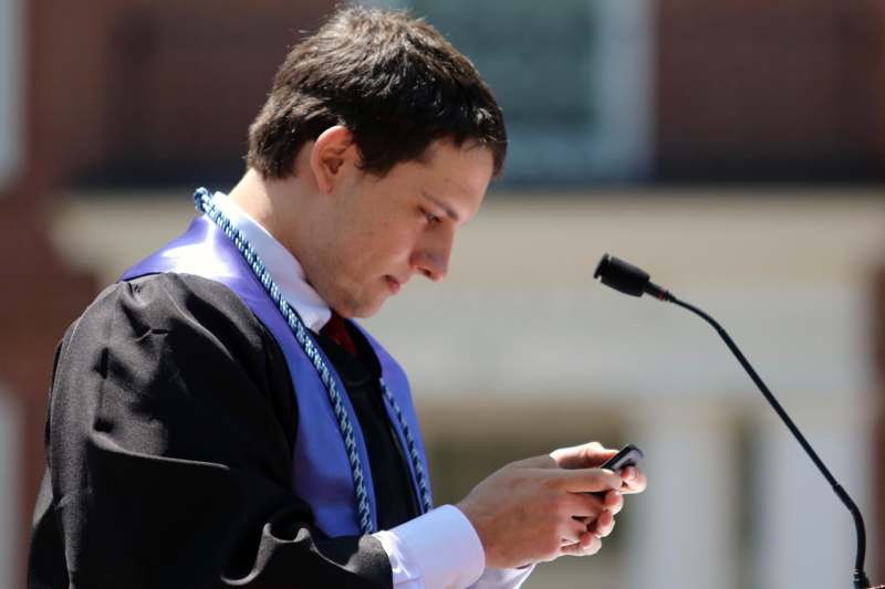 a man in a graduation gown looking at his phone