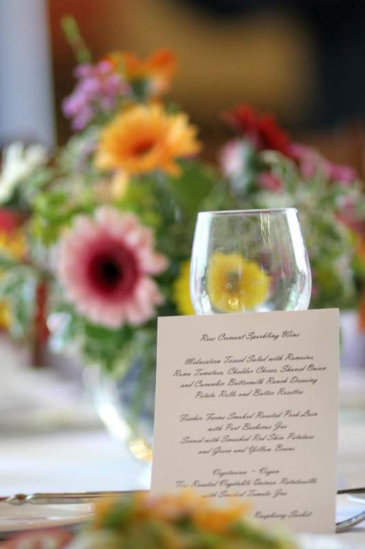 a wine glass with a menu in front of a bouquet of flowers