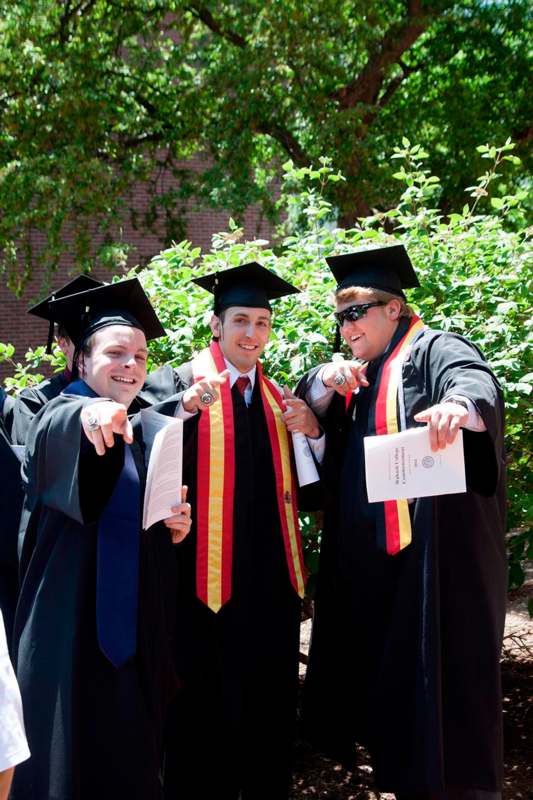 a group of men in graduation gowns and caps pointing at something