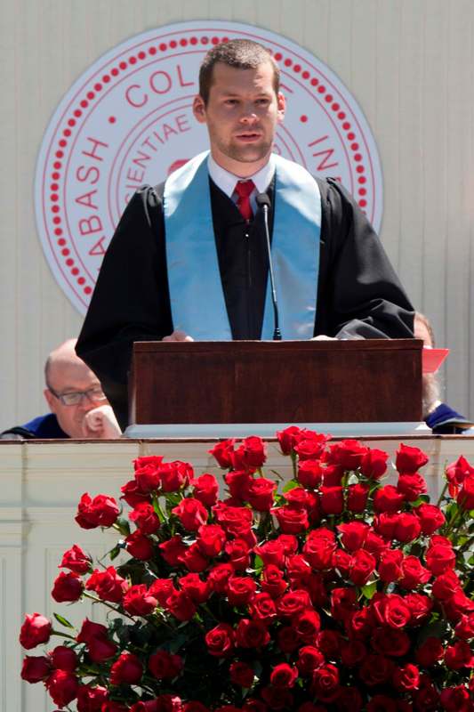 a man in a robe standing at a podium with a bunch of roses
