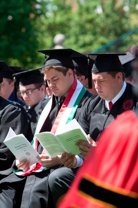 a group of people in graduation gowns and caps reading books