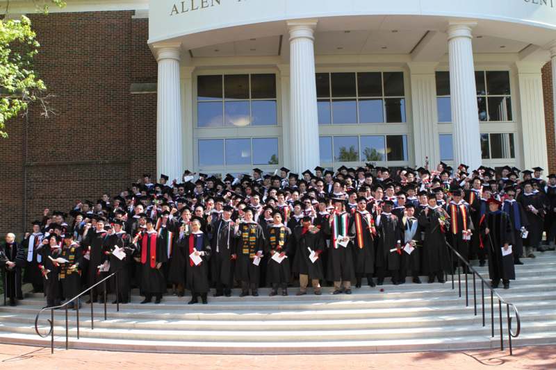 a group of people in graduation gowns and caps posing for a photo