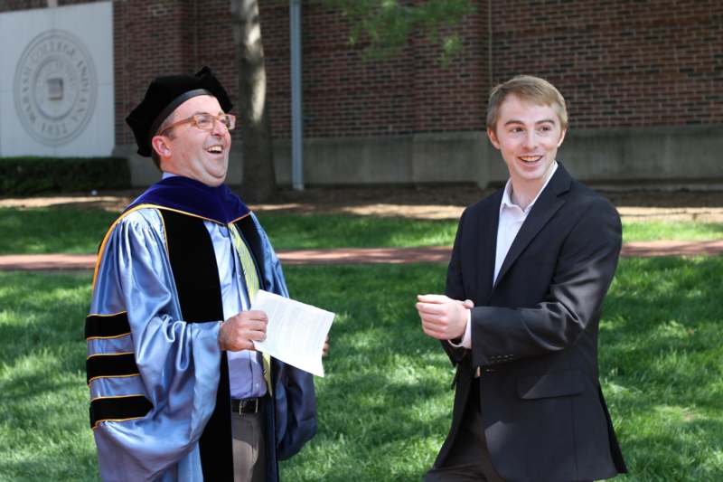 a man in a graduation gown and a man in a suit