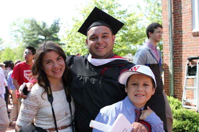 a man in a graduation gown and cap with a boy and a woman