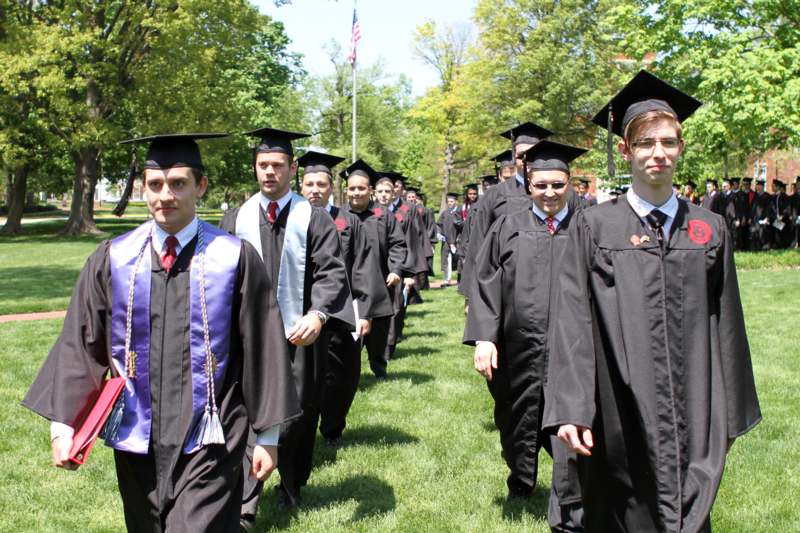 a group of people in graduation gowns and caps walking on grass