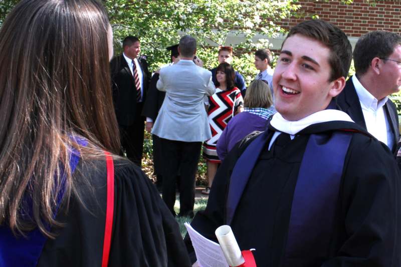 a man in a graduation gown talking to a woman