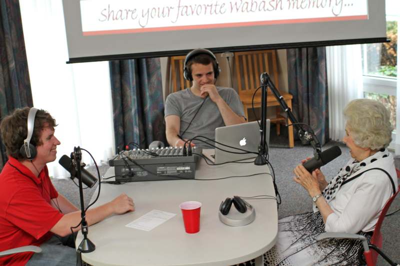 a group of people sitting at a table with microphones and a laptop