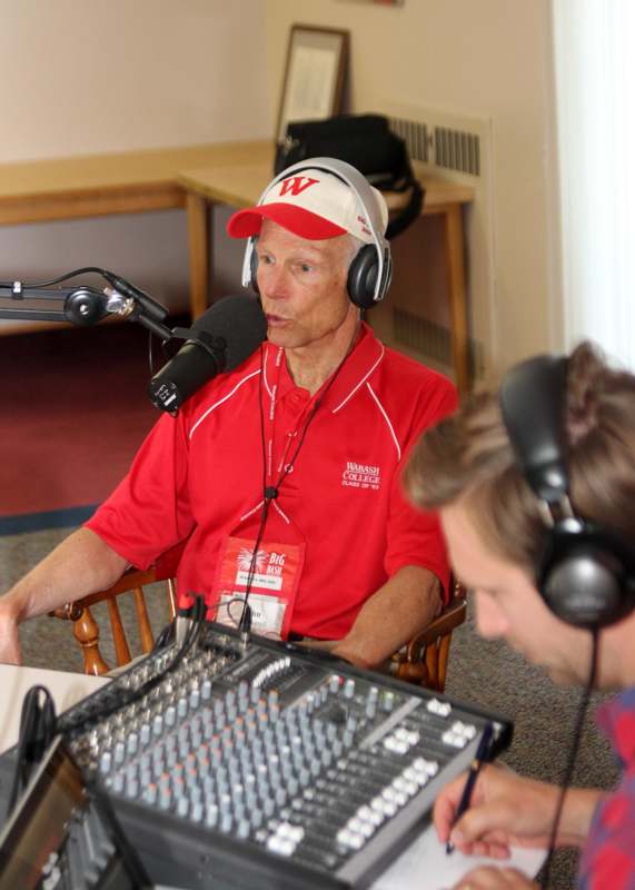 a man in a red shirt talking into a microphone