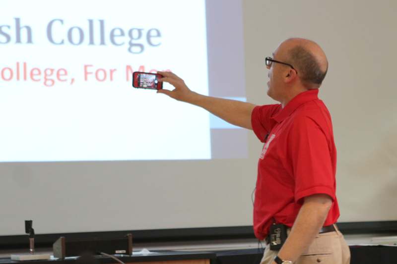 a man in a red shirt taking a picture of a screen
