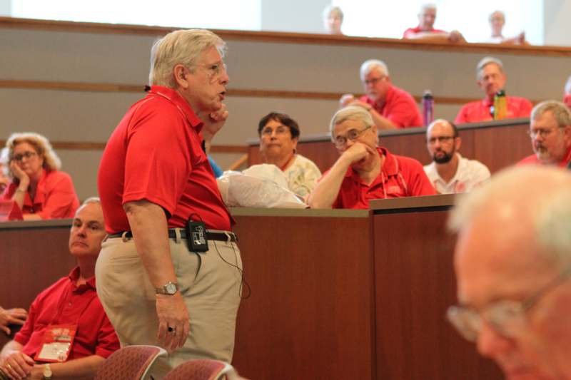a man in red shirt talking to a group of people