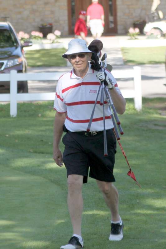a man walking on a golf course carrying golf clubs