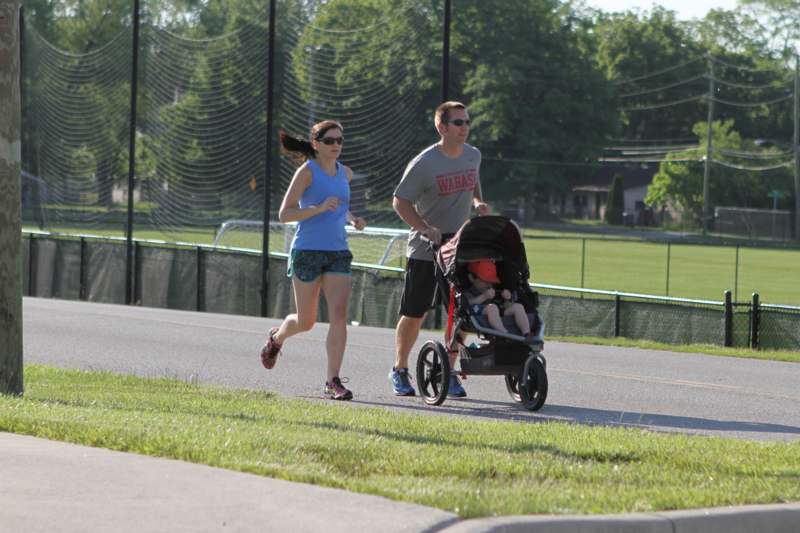 a man and woman running with a baby in a stroller