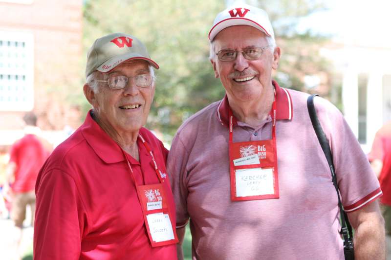 two men wearing matching red shirts and hats