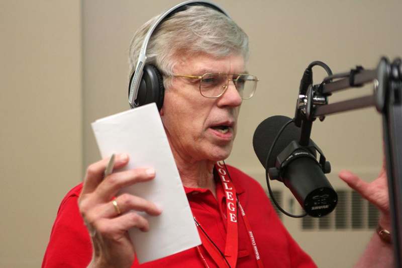 a man wearing headphones and holding a piece of paper in front of a microphone