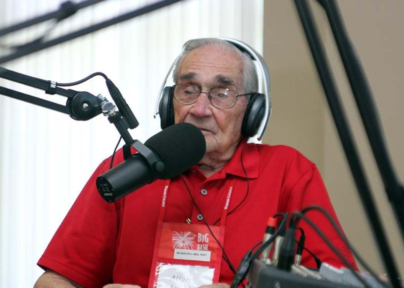 an old man wearing headphones and talking into a microphone
