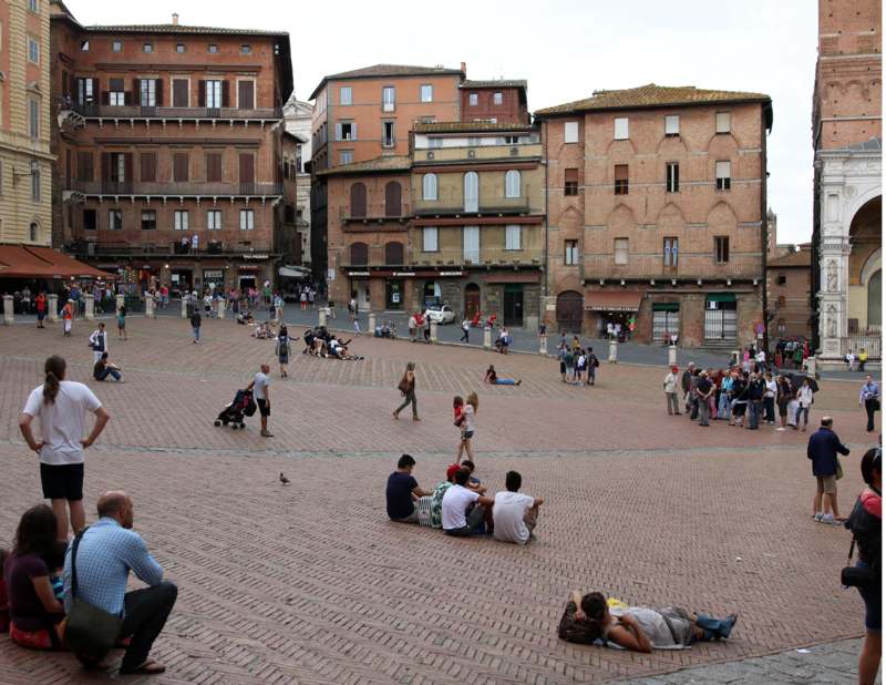 a group of people sitting on a brick plaza