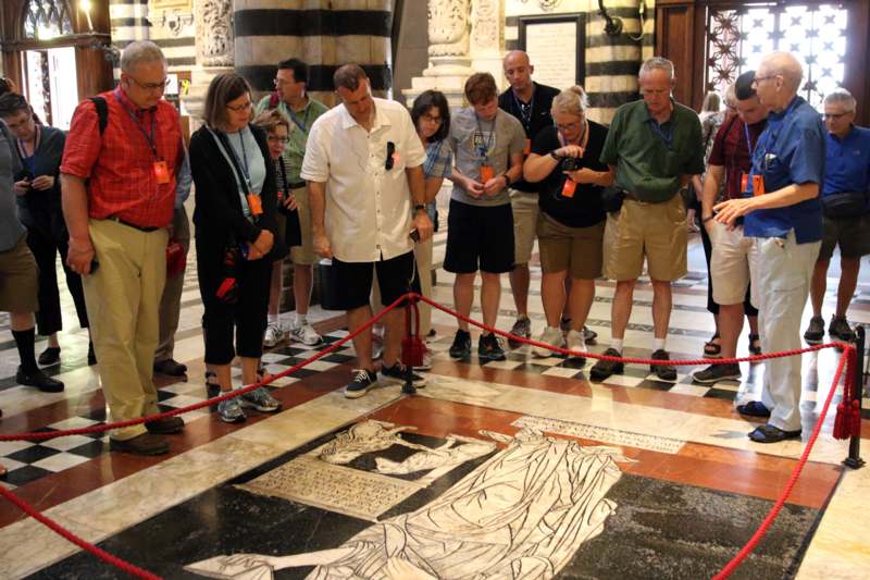 a group of people standing around a floor with a red rope