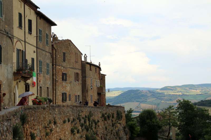 a stone wall with buildings and hills in the background
