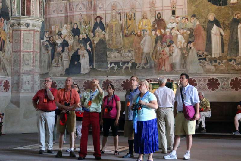 a group of people standing in a room with a mural on the wall