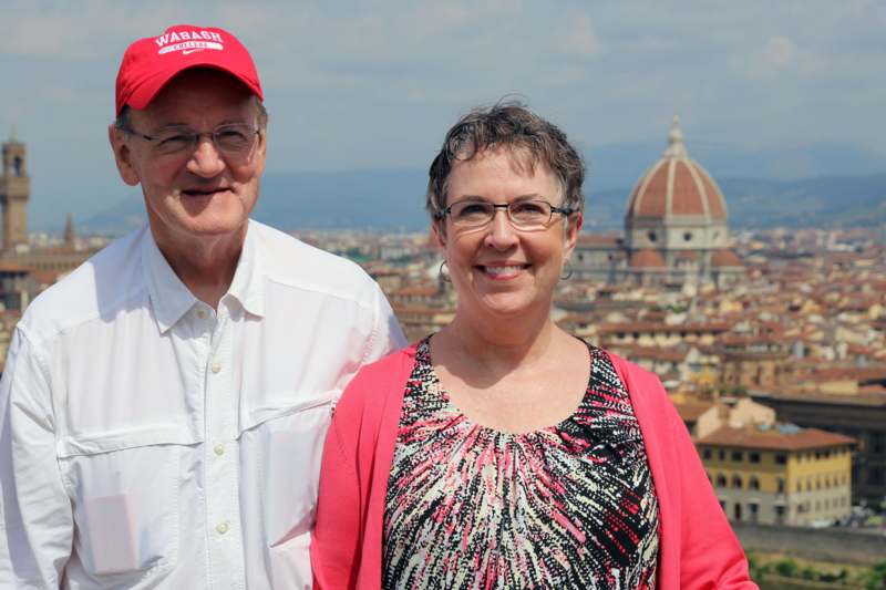 a man and woman standing together in front of a city