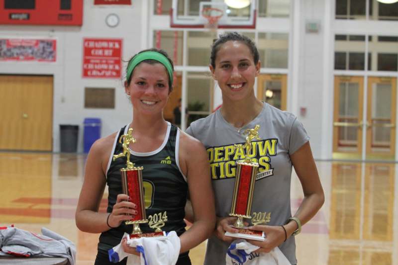 two women holding trophies in a gym