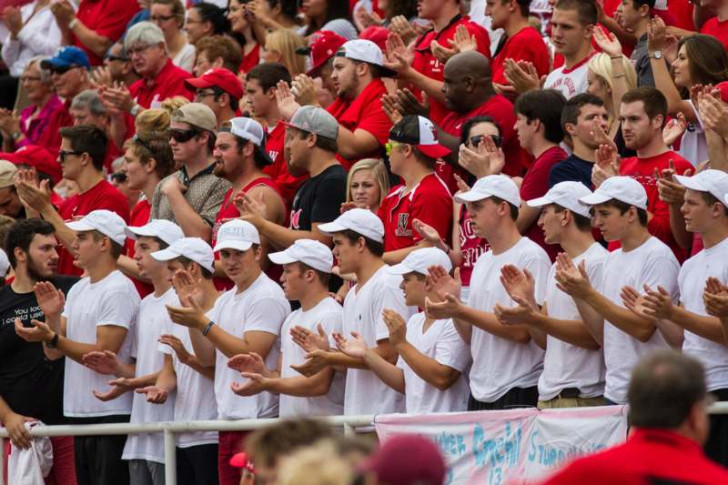 a group of people in red shirts and hats clapping