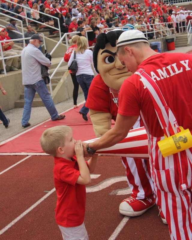 a boy in red and white striped pants kissing a man's hand