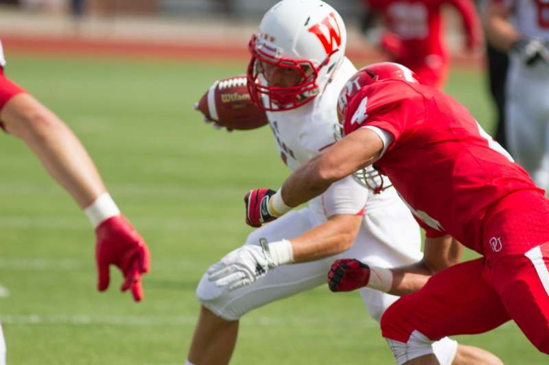 a football player in a red uniform running with a football