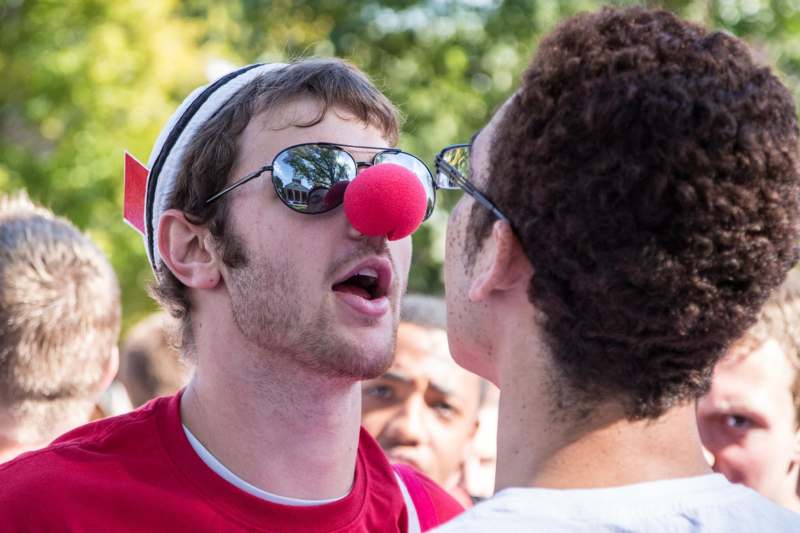 a man with a red nose and sunglasses looking at another man