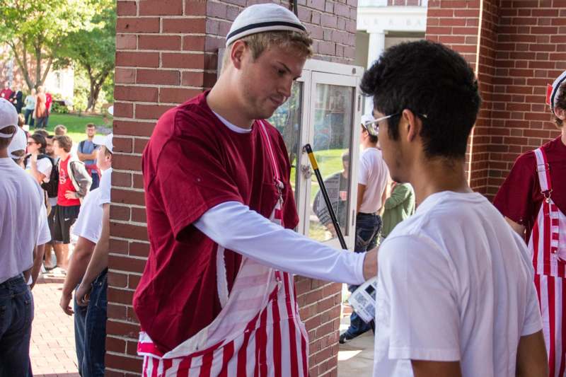 a man in a red and white striped apron shaking hands with another man