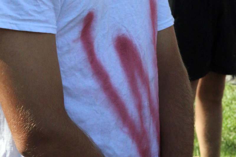 a person wearing a white shirt with red paint on it