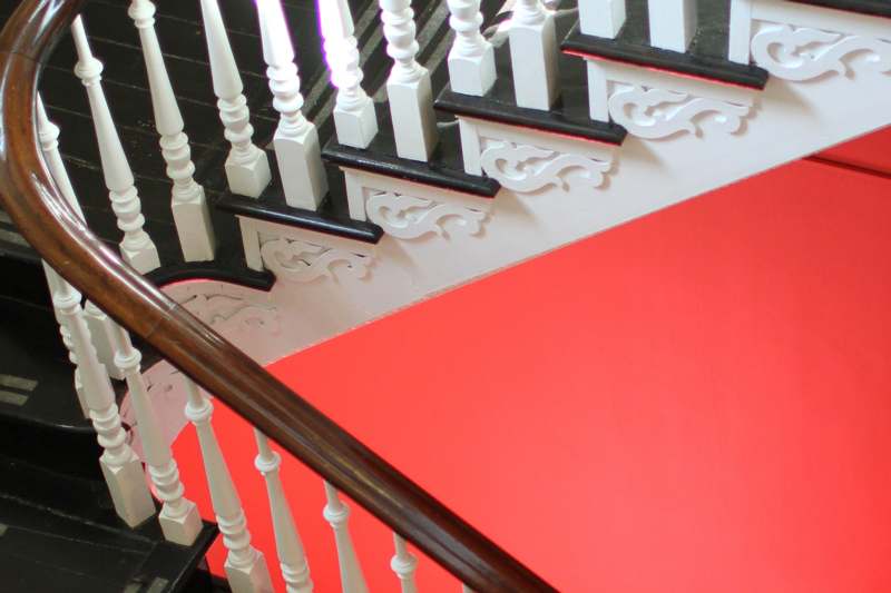 a staircase with white railings and red wall