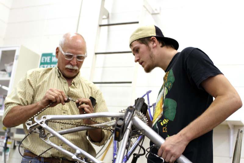 a man and a young man working on a bicycle