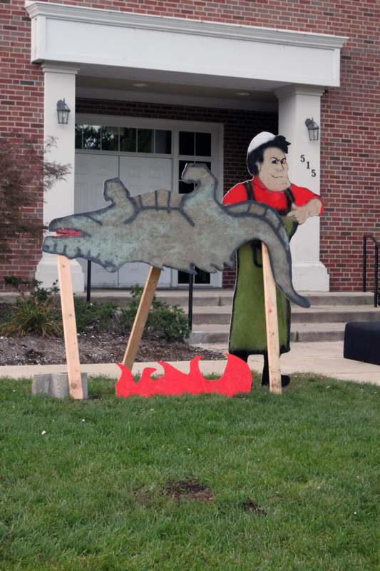 a cardboard cutout of a man and a crocodile in front of a house