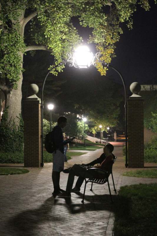 a man sitting on a bench under a lamp post
