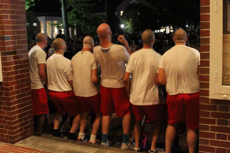 a group of men in white shirts and red shorts standing in a line