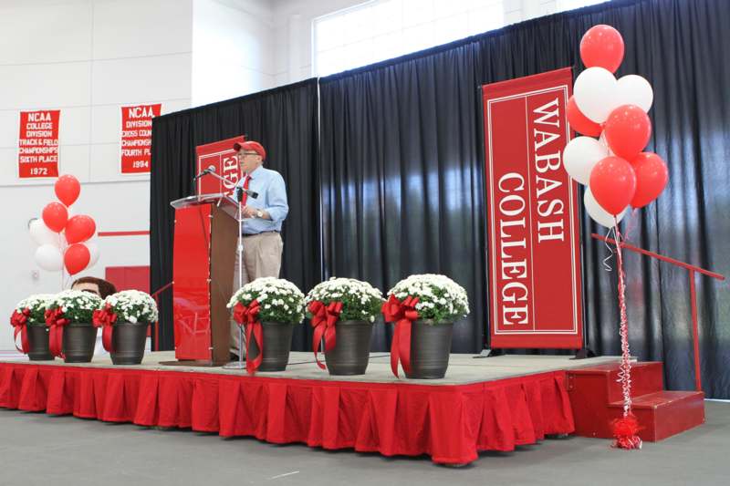 a man standing at a podium with red and white balloons