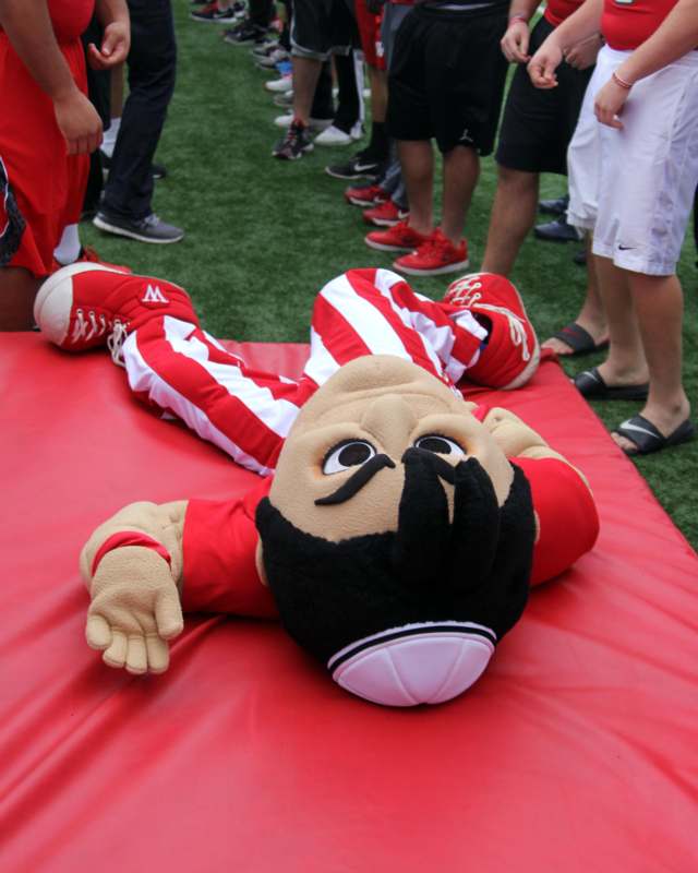 a person lying on a red mat with a person wearing a black head mask