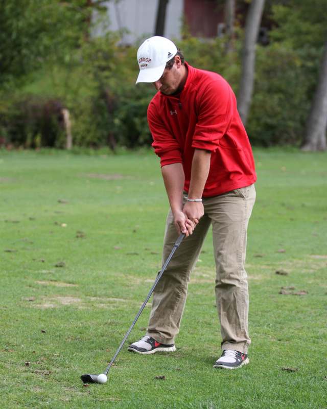 a man in a red shirt and white hat playing golf
