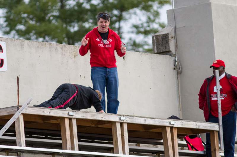 a man in a red jacket standing on a wooden bleachers