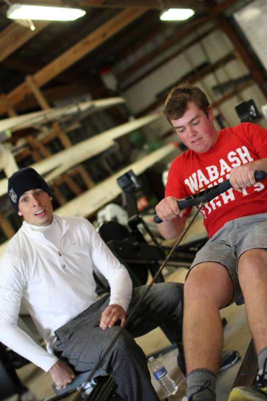 a man sitting on a chair with another man on a rowing machine