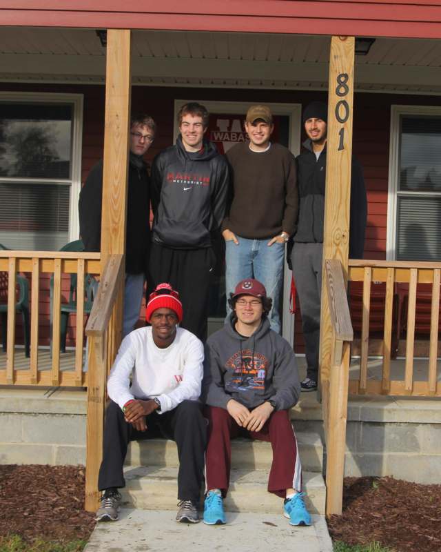 a group of men posing for a photo on a porch