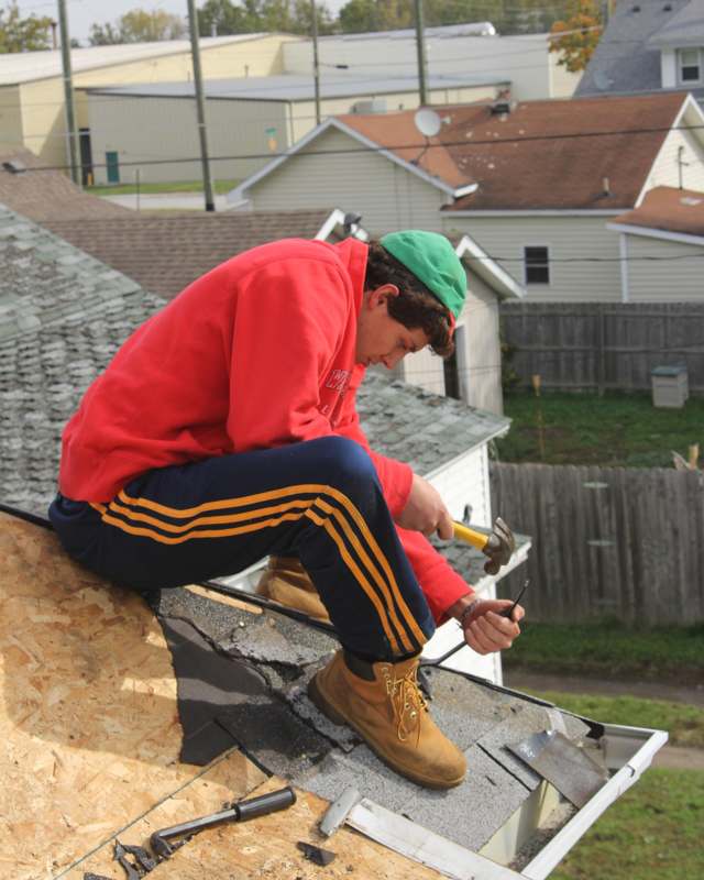 a man sitting on a roof with hammers