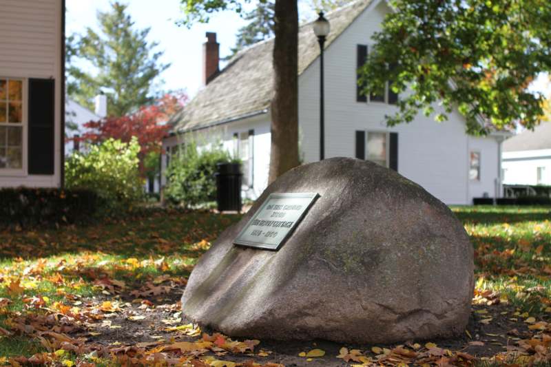 a large rock with a sign on it in front of a house