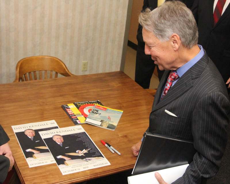 a man in a suit holding a folder and a folder on a table