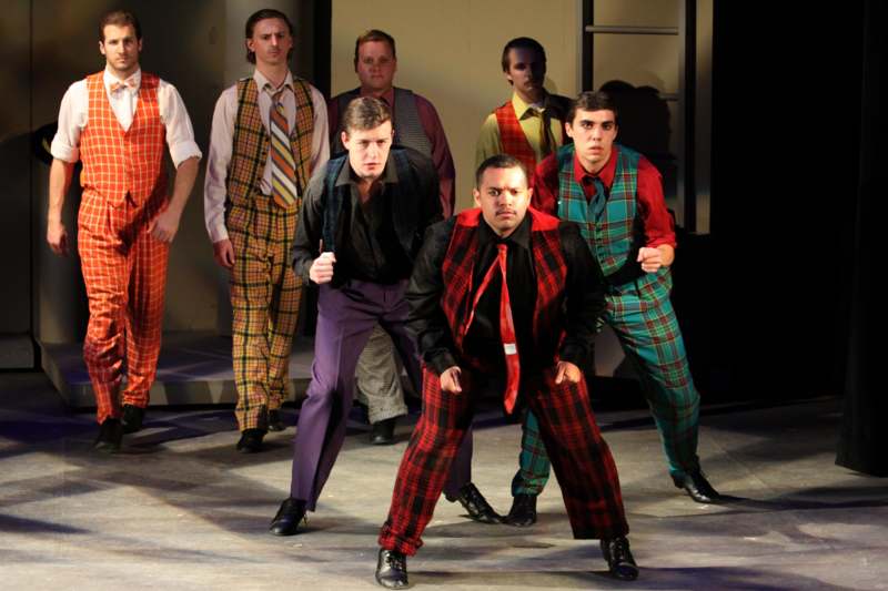 a group of men wearing plaid vests and standing on a stage