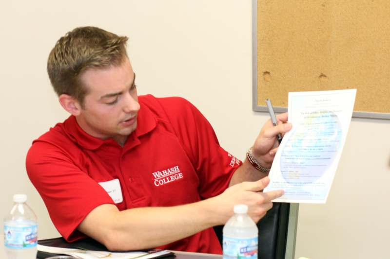a man in a red shirt holding a pen and looking at a piece of paper