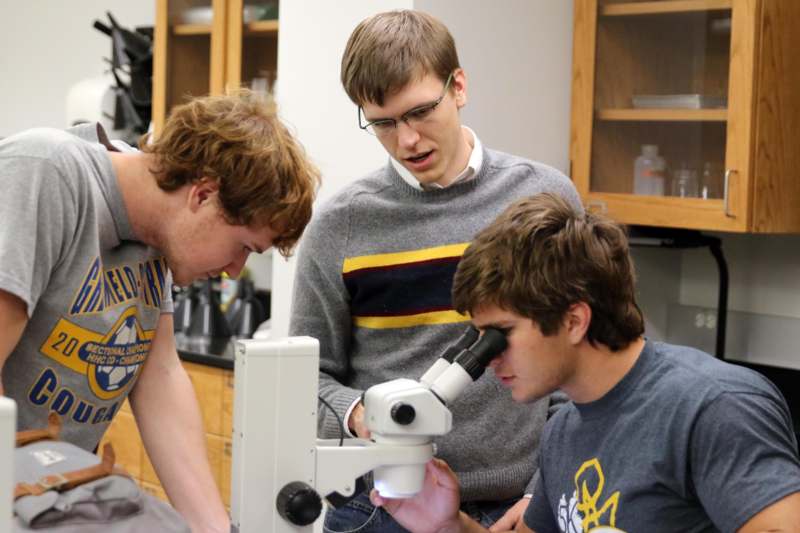 a group of men looking through a microscope