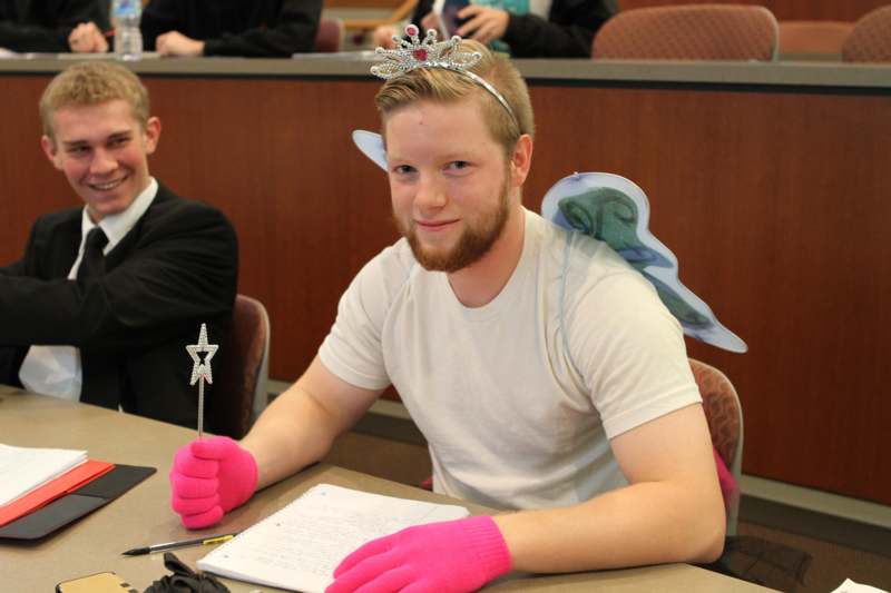 a man wearing a crown and gloves sitting at a table